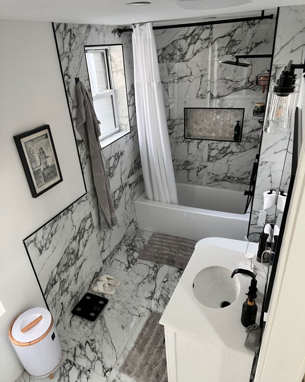 A bathroom we renovated: marble tile floor to ceiling, a new tub, black fittings and a white vanity
