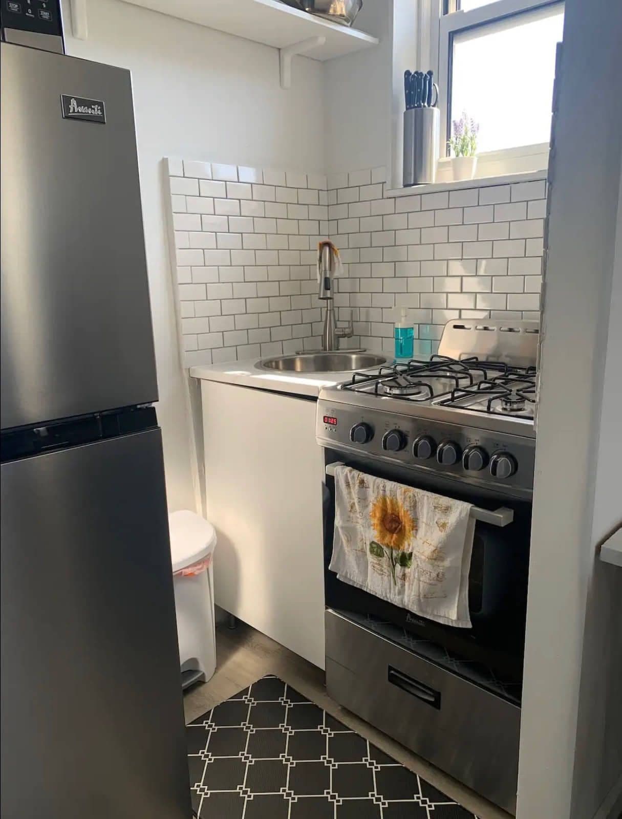 The kitchenette — white subway tile, a stainless fridge and a gas range set into a run of counter.