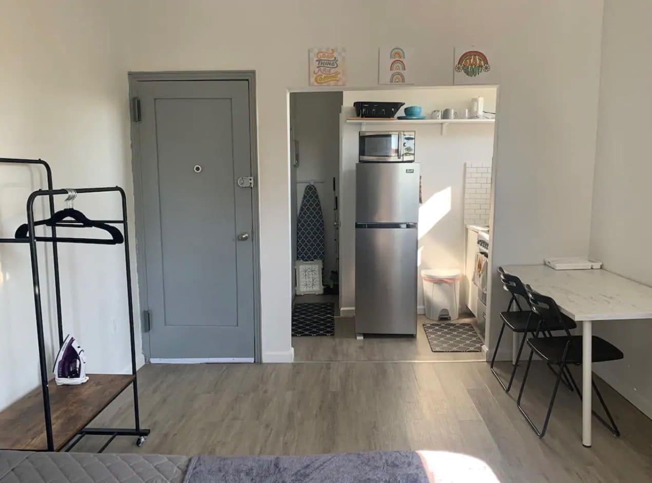 The finished studio looking toward the entry door, with the kitchen along the right-hand wall and a table under the window.