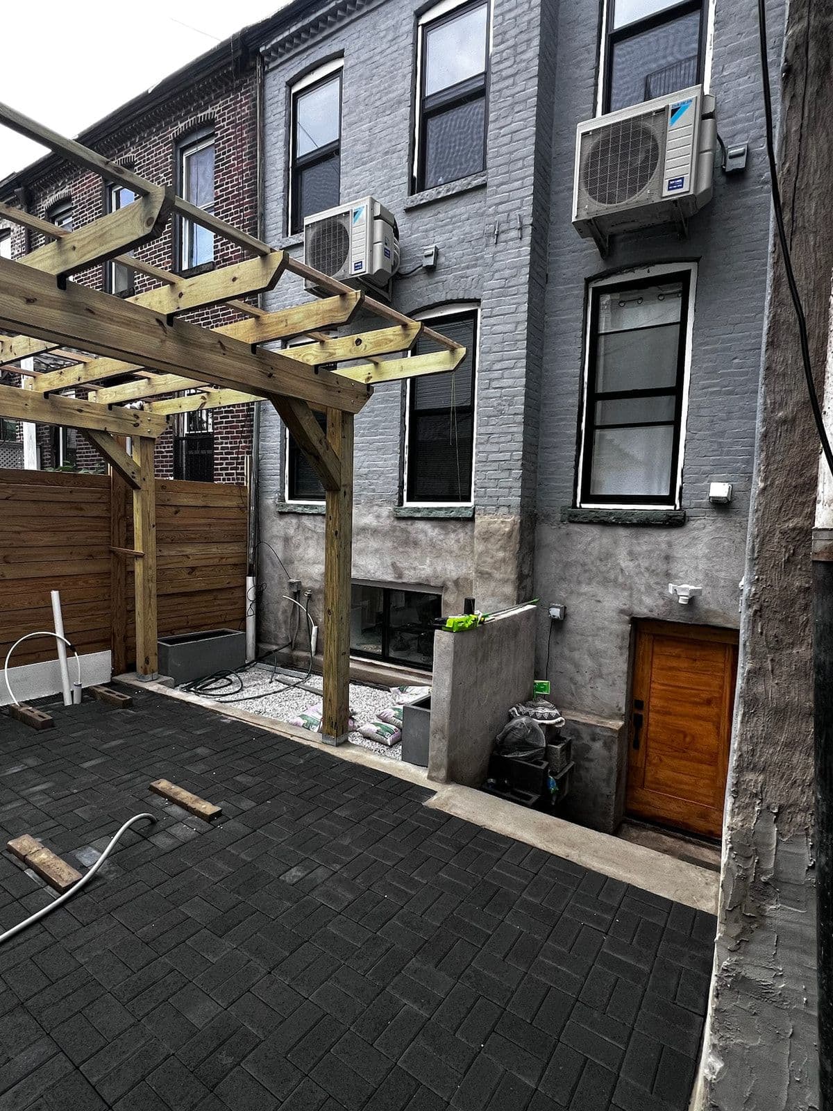 Near the end: the pergola over the finished paver patio, with the new cedar fence, rendered walls and a new back door.
