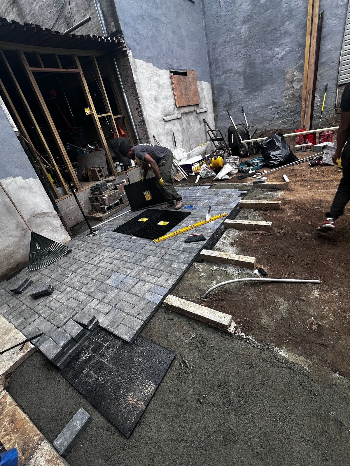 Pavers going down over the compacted base, laid out from the back door forward.